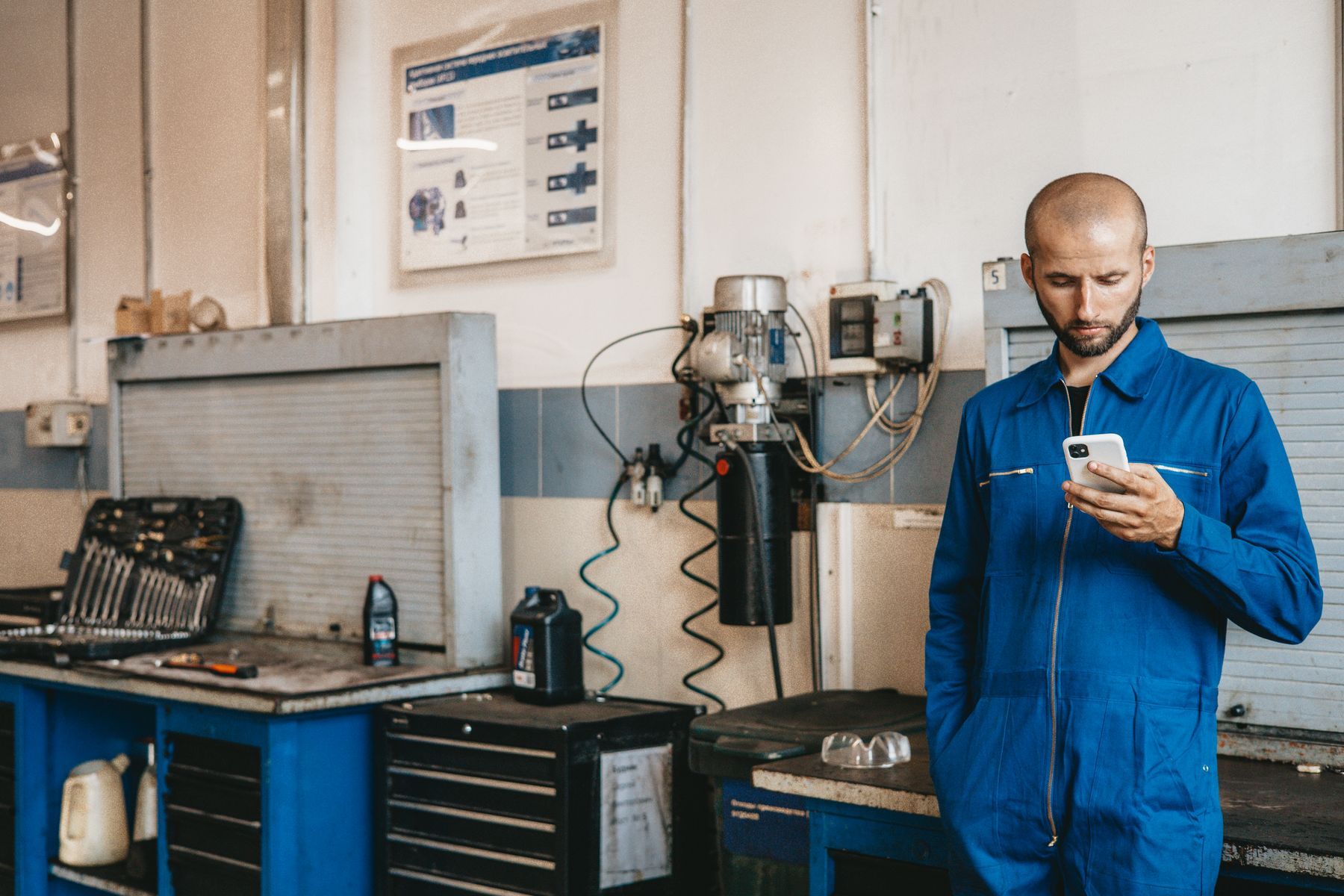 Mechaniker mit Smartphone in der Werkstatt